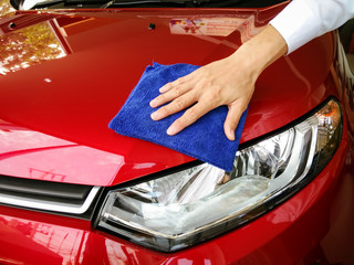 Selective focus hand with blue microfiber cloth cleaning red car.copy space.