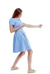 back view of standing girl pulling a rope from the top or cling to something. Isolated over white background. Skinny girl in a blue dress and holding on to the rope.