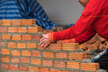 Worker installing red brick for construction site