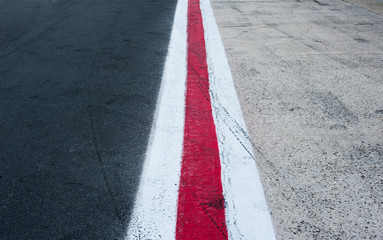 Vertical red and white lines on dark grey asphalt