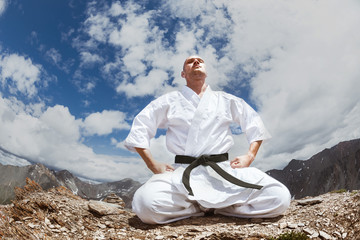Naklejka na ściany i meble Karate man sits in yoga pose