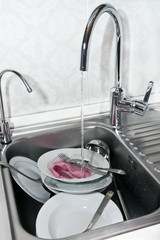 dishwashing in sink under running water