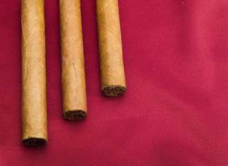 Three Cigars on red satin