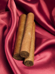 Three Cigars on red satin