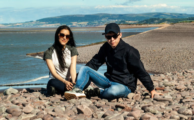 Happy young couple in love relaxing in a  beach of Minehead, UK  enjoying ocean view together.