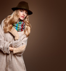 Fall Fashion. Model Woman in Autumn Fashion Outfit, Stylish Coat Trendy Hat, in Scarf, Gloves. Fashion Makeup. Playful Blonde girl with Wavy hair. Fall Autumn Winter. Fashion Pose. Creative Vintage