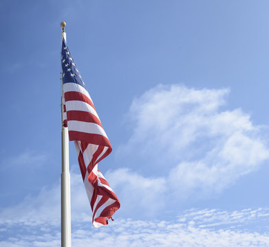 American flag on the pole against blue sky and clouds