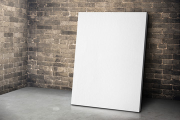 Blank white canvas frame leaning at grunge brick wall and wood f