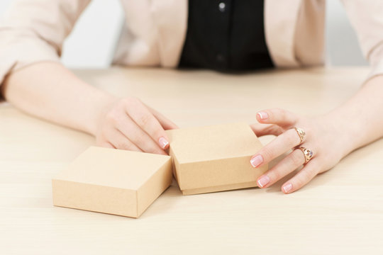 Woman holding two carton boxes on table. Female hands with post packages, preparing to open. Delivery service. online shopping, parcel opening concept