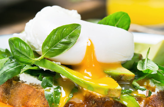 Poached egg with avocado, arugula and basil leaves
