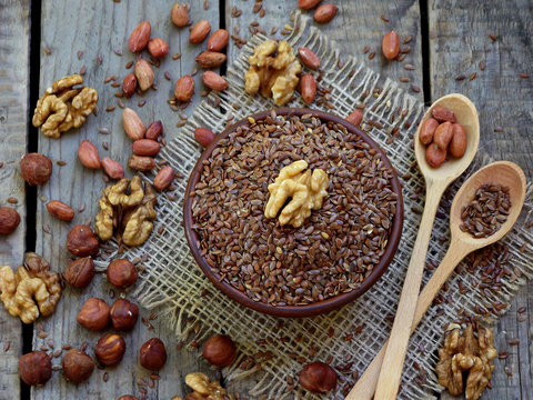 flax seeds in bowl and walnuts, hazelnuts, peanuts. selective focus