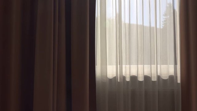 Apartment curtains in dark room, sunlight shining through