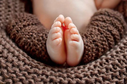 Close up picture of new born baby feet on knitted plaid