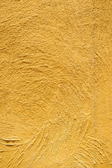 Close-up detail of a rough, yellow-orange skim coat wall, vertical orientation. Architecture and design concept.