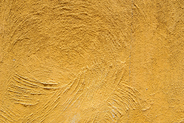 Close-up detail of a rough, yellow-orange skim coat wall. Architecture and design concept.