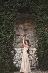 Beautiful girl, model near the wall of leaves and bushes in park