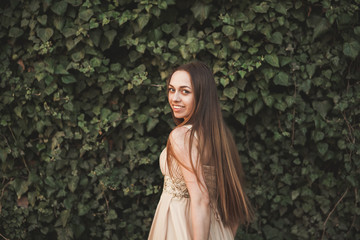 Beautiful girl, model near the wall of leaves and bushes in park