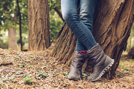 Close-up of female legs in jeans and boots in autumn park