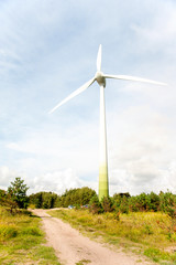 Fototapeta premium Energy generator wind turbine on dramatic cloudy blue sky backgr