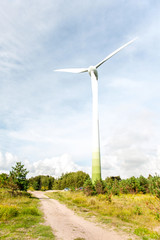 Fototapeta premium Energy generator wind turbine on dramatic cloudy blue sky backgr
