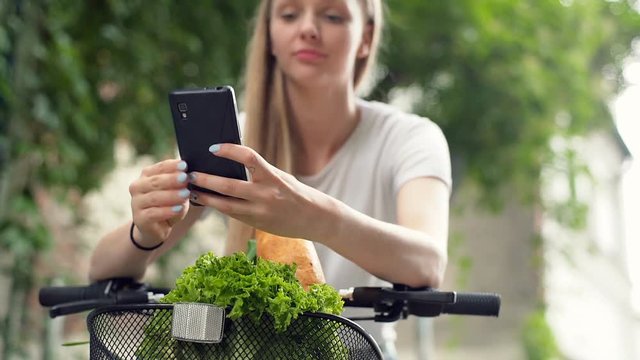 Pretty girl leaning on handlebars and doing selfies on smartphone
