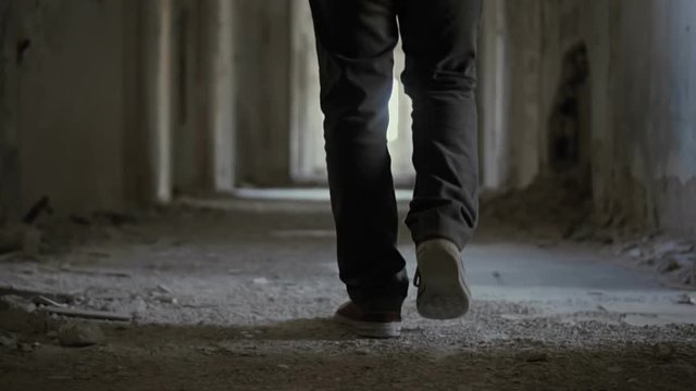 Hooded young man inside destroyed abandoned building,slow motion,dramatic