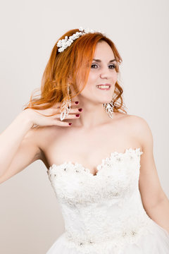 red-haired bride in a wedding dress, bright unusual appearance. Beautiful wedding hairstyle and bright make-up
