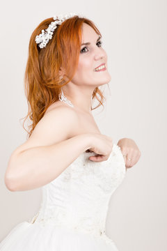 red-haired bride in a wedding dress, bright unusual appearance. Beautiful wedding hairstyle and bright make-up