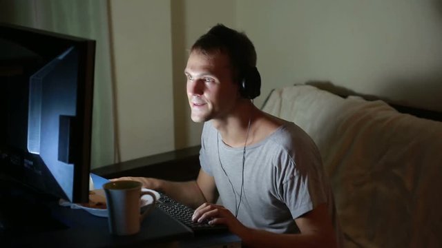 man playing video games on your computer. late at night on the computer gamer