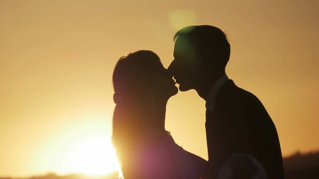 Silhouette kissing at sunset bride and groom