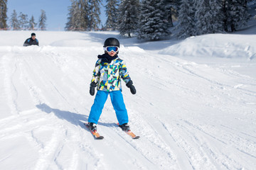 Cute little boy, skiing happily in Austrian ski resort in the mo