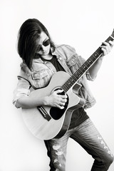 Fototapeta na wymiar Fashion portrait of a teenager playing guitar in studio wearing jeans jacket