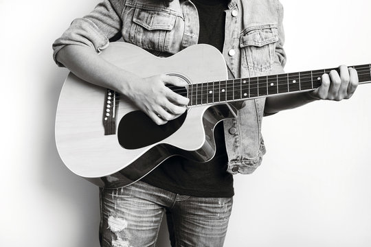 Portrait of a teenager playing guitar in studio wearing  jeans jacket