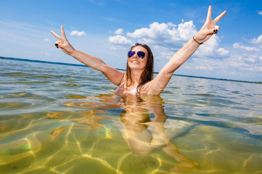 Beautiful young woman in the sea. Beautiful woman having a fun while swimming in the lake/ Girl in bikini shows the letter "v"