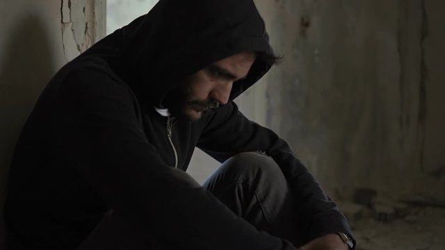 Hooded young man inside destroyed abandoned building,slow motion,dramatic