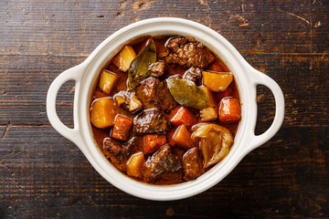 Beef meat stewed with potatoes, carrots and spices in ceramic po - obrazy, fototapety, plakaty