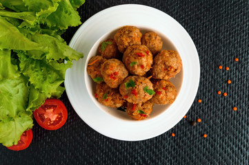 Meat balls with chilli and herbs in a white bowl. The top view