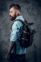 Bearded tattooed backpacker posing in studio.