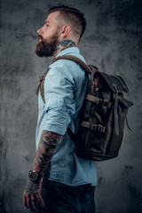 Fototapeta na wymiar Bearded tattooed backpacker posing in studio.