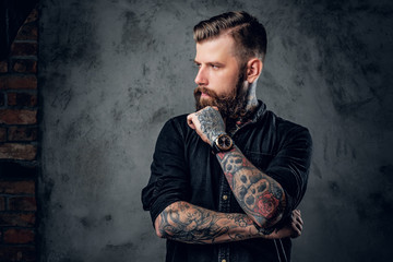 Bearded hipster with tattooe on his arms.