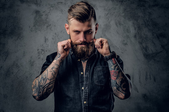 Bearded hipster with tattooe on his arms.