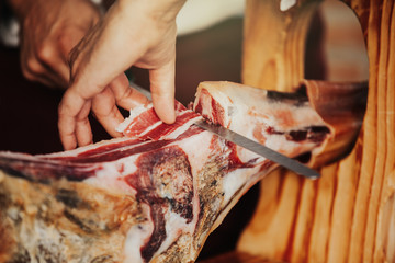 Spanish iberian ham being served. Man hands cutting it.
