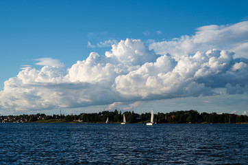 Widok na jezioro w po którym żeglują jachty. Na niebie widać rozbudowujące się chmury Cumulus.