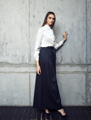 Fashion model wearing white shirt and long black skirt posing in studio