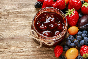 Jar of strawberry jam and raw fruits