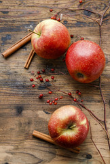 Red apples and cinnamon sticks on wood