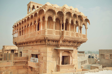 Carved tower with stone balconies of ancient indian house in old town in India