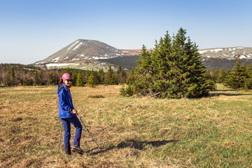 Female hiker walking under the rays of the morning sun in the mo