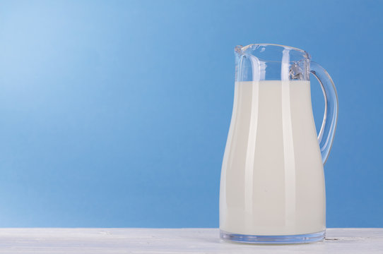 Milch Krug aus Glas auf hell blau Hintergrund.