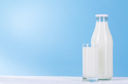 Flasche und Glas Milch auf hell blau Hintergrund.